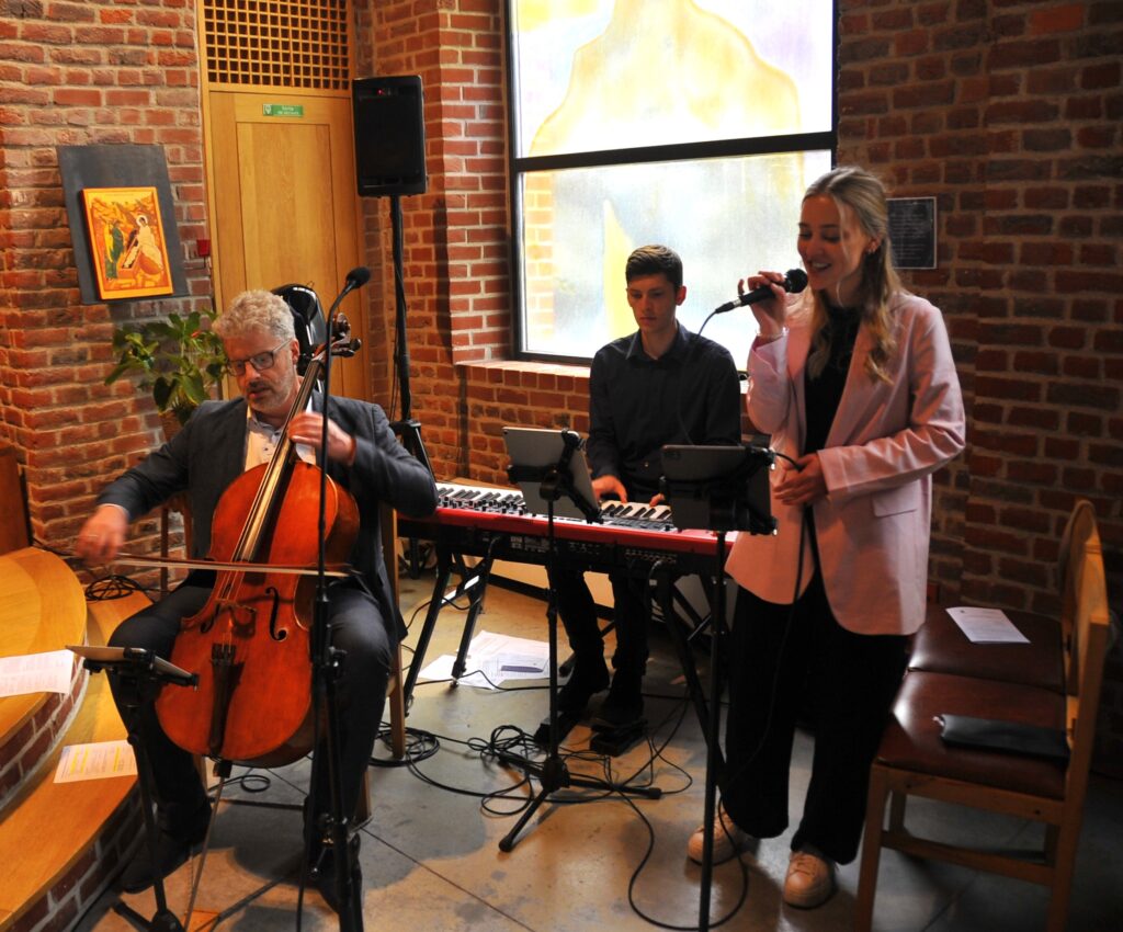 Musicisti suonano violoncello, tastiera e cantano in concerto
