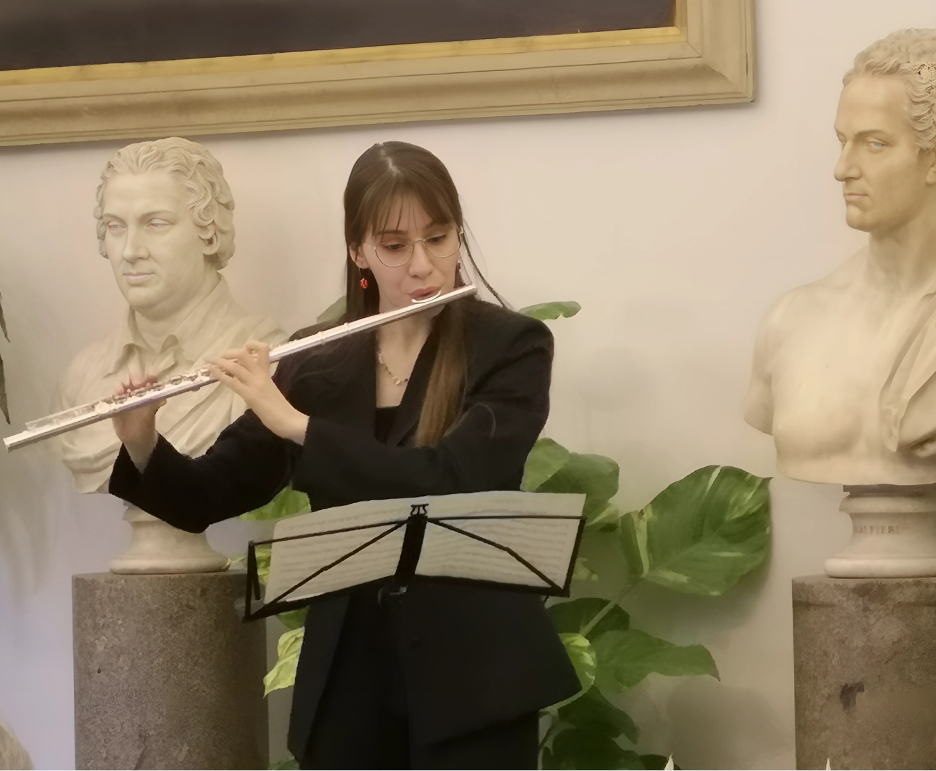 Musicista suona flauto davanti a statue classiche.