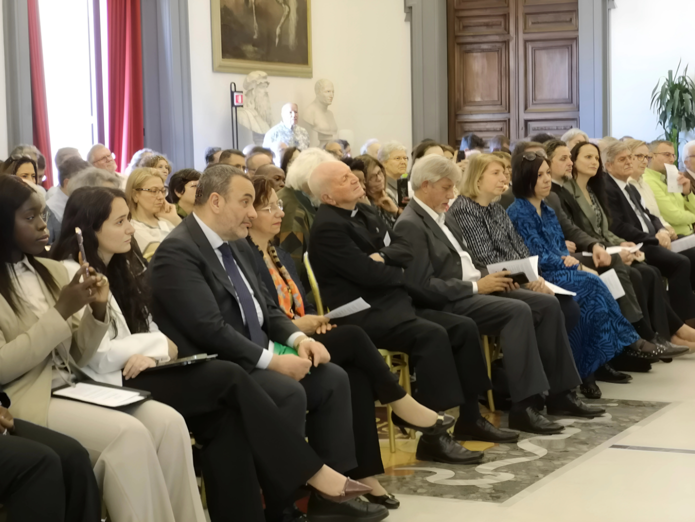 Persone sedute durante un evento formale in sala.