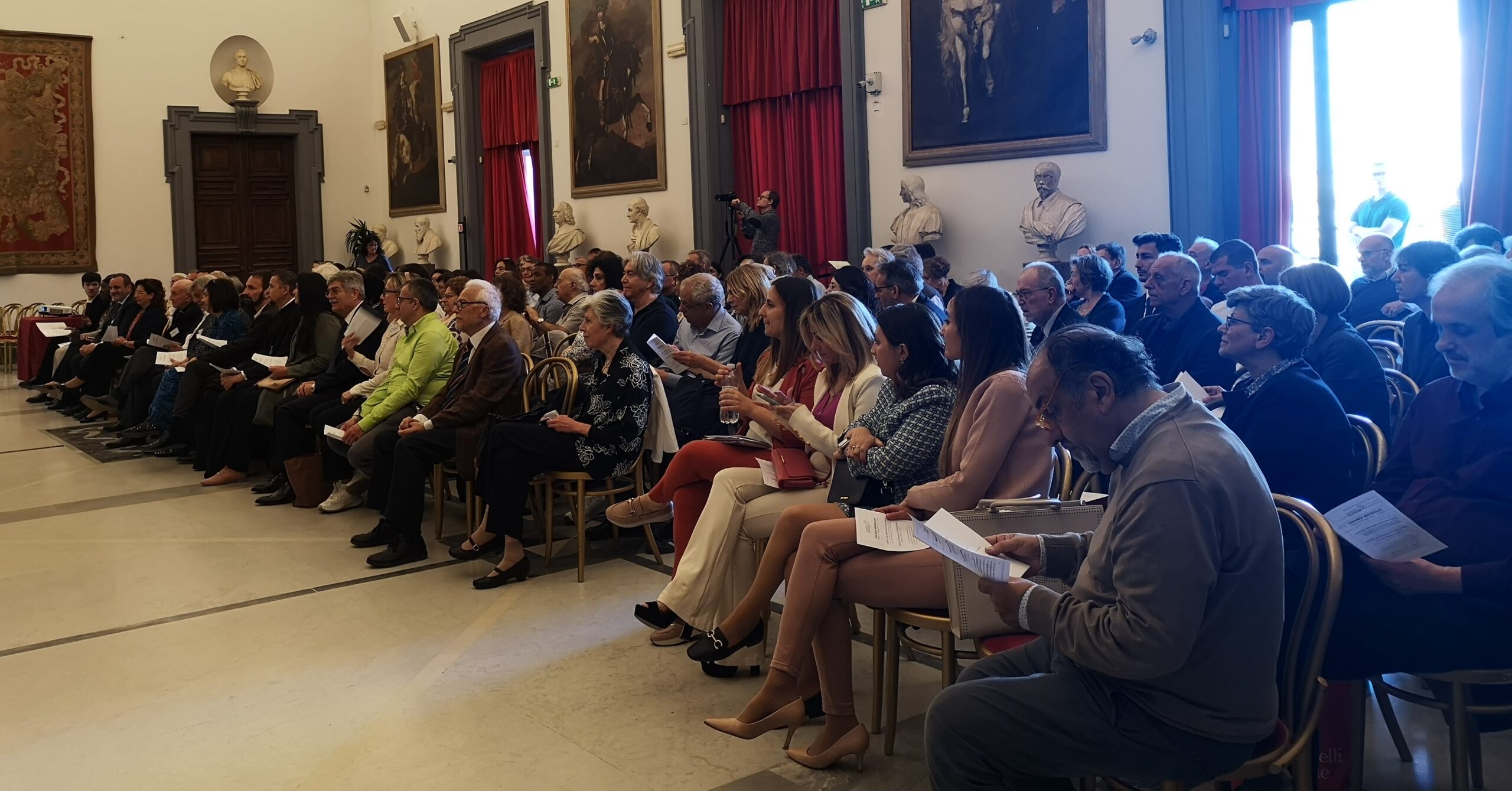 Persone sedute in sala conferenze, evento formale.