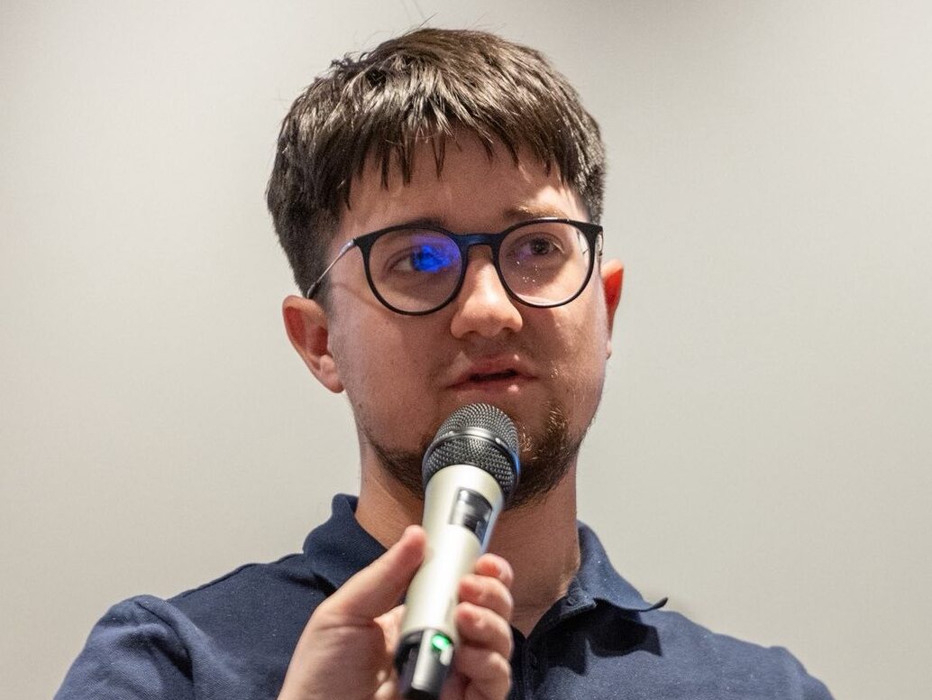 Uomo con occhiali parla al microfono